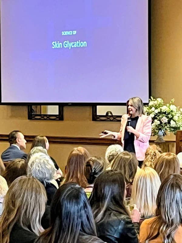 Zanoli speaking on stage in pink blazer